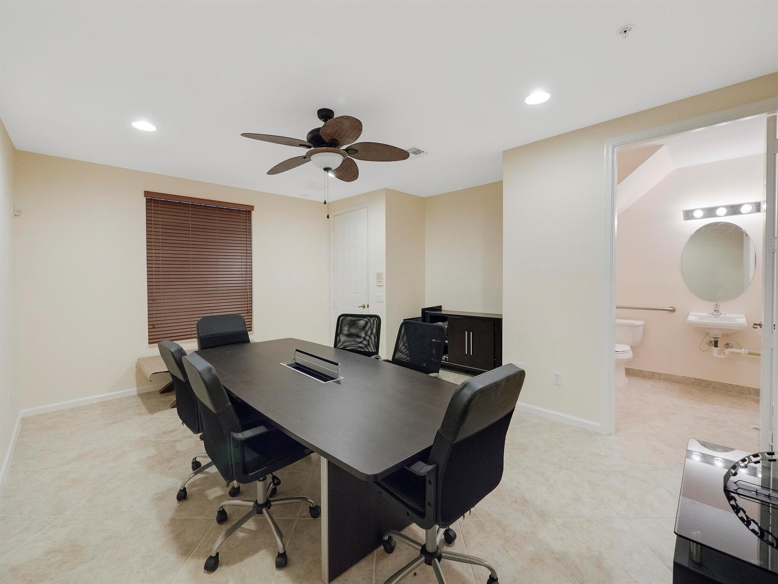 A conference room features a dark table, rolling chairs, a ceiling fan, and an attached bathroom — 1859 Vía Granada, Boynton Beach FL 33426, BOYNTON BEACH, FL