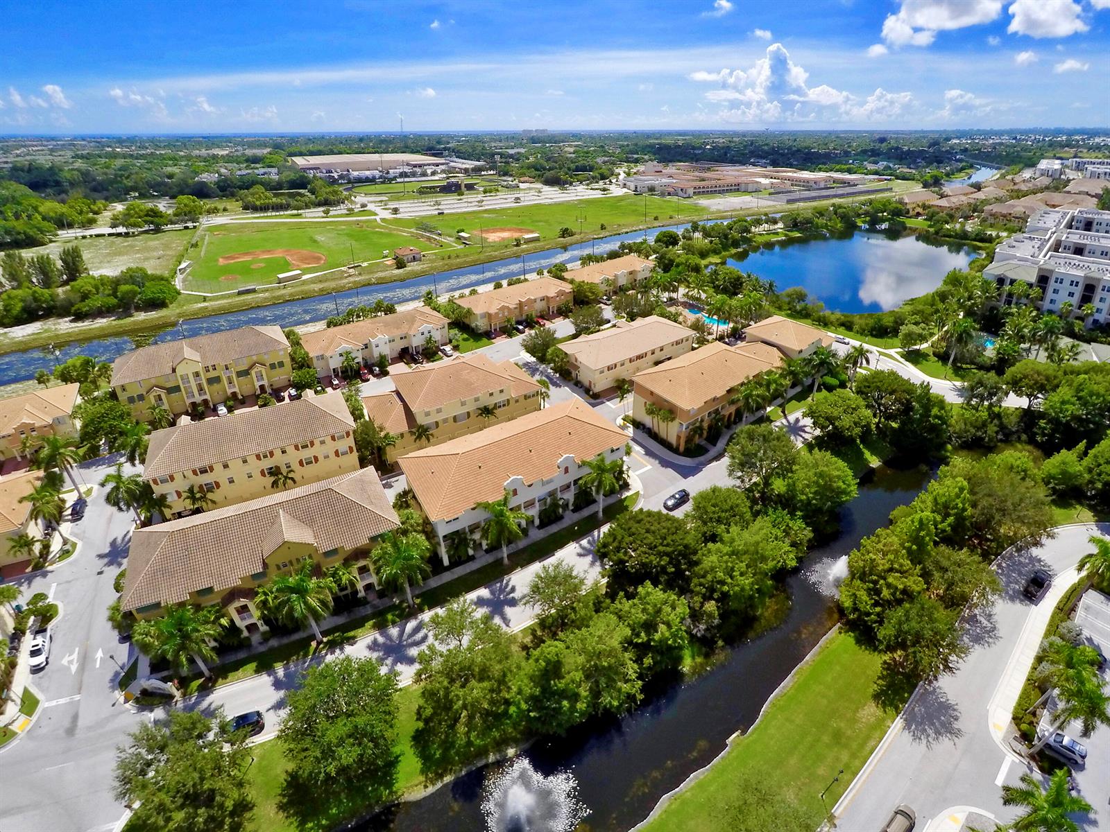 An aerial view shows multi-story apartment buildings with tile roofs surrounded by canals and landscaping — 1859 Vía Granada, Boynton Beach FL 33426, BOYNTON BEACH, FL