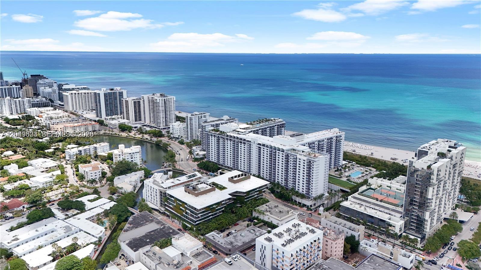 An aerial view shows high-rise apartment buildings along a beach and a coastal waterway — 2301 Collins Ave # 414, Miami Beach FL 33139, MIAMI BEACH, FL