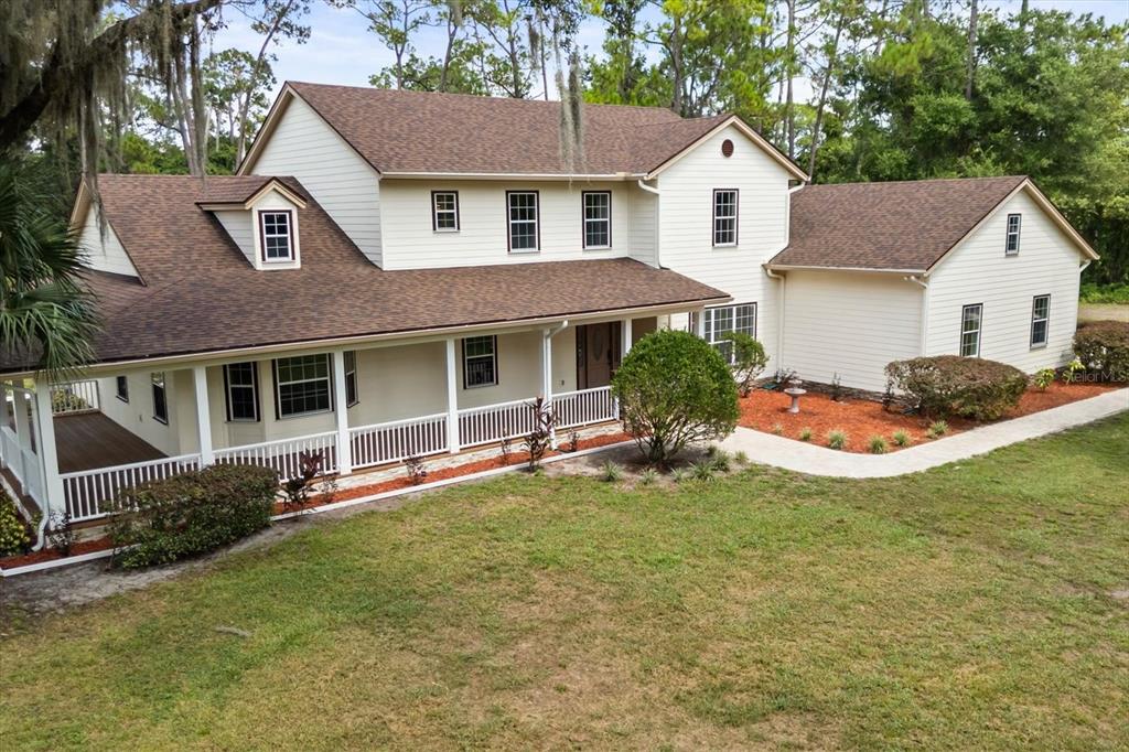 A two-story house with cream siding, a brown shingled roof, and a wide front porch — 27012 GRAND OAK LANE, TAVARES, FL