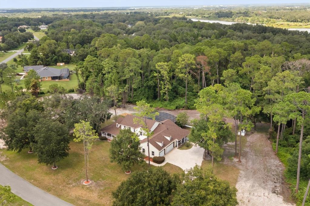 An aerial view shows a large house with a pool enclosure surrounded by dense woods — 27012 GRAND OAK LANE, TAVARES, FL
