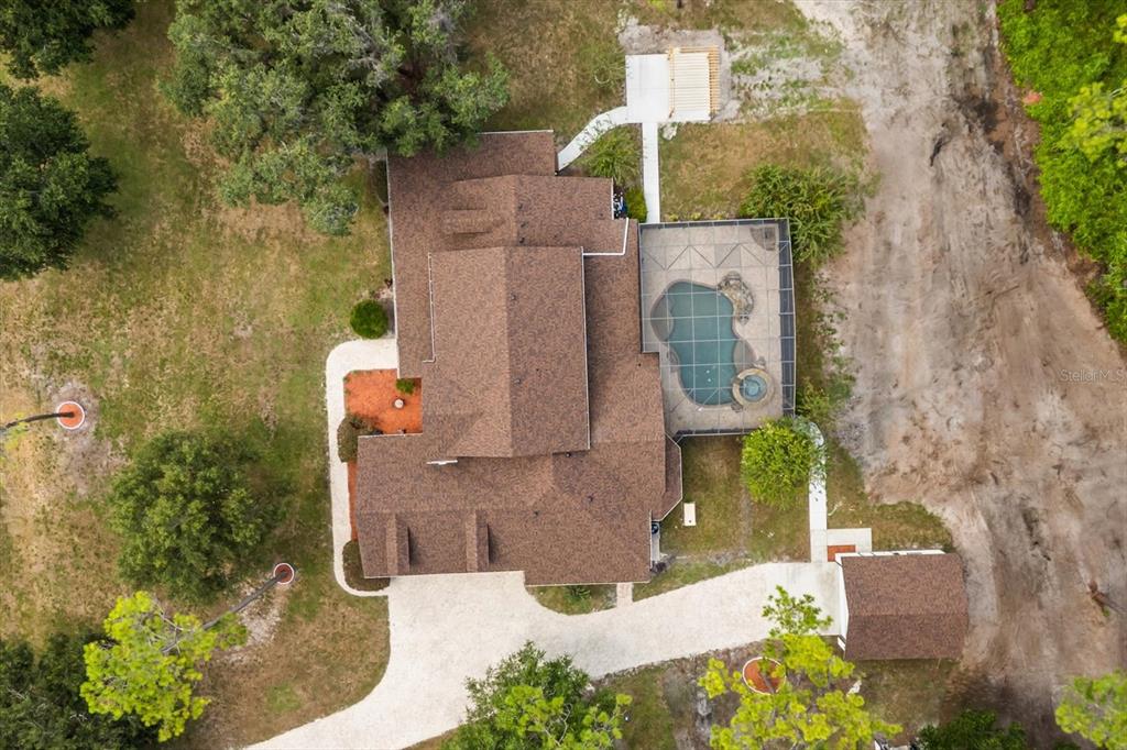 An aerial view shows a house with a brown roof, pool enclosure, and detached garage — 27012 GRAND OAK LANE, TAVARES, FL