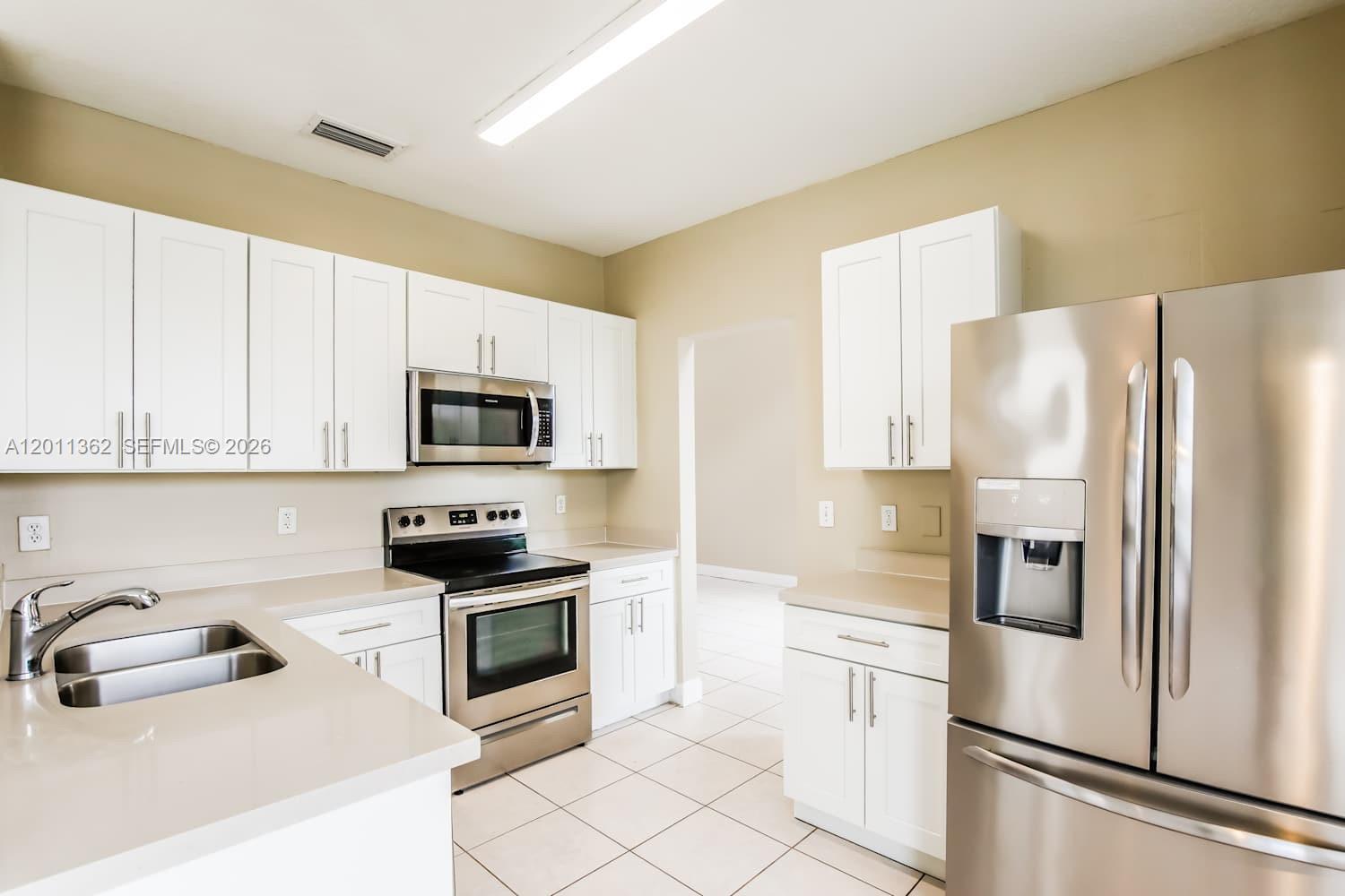 A kitchen features white cabinets, stainless steel appliances, and light-colored countertops — PEMBROKE PINES, FL