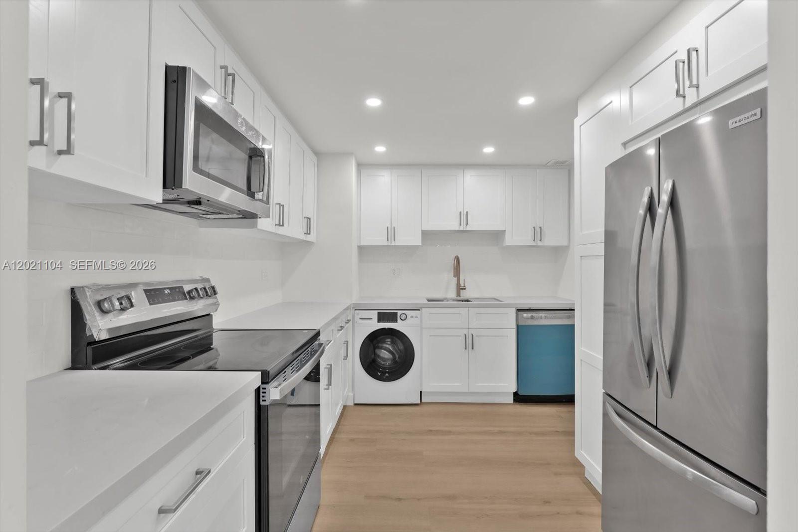 A modern kitchen features white cabinetry, stainless steel appliances, and a built-in washing machine — 2451 Brickell Ave # 6N, Miami FL 33129, MIAMI, FL