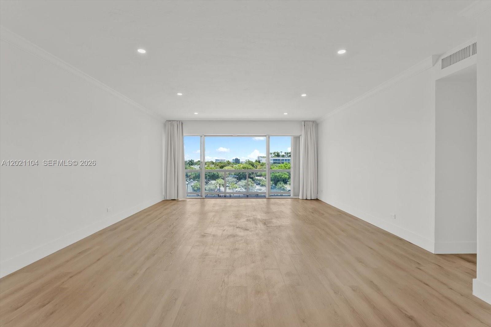An empty room features light wood-look flooring, white walls, recessed lighting, and a large window — 2451 Brickell Ave # 6N, Miami FL 33129, MIAMI, FL