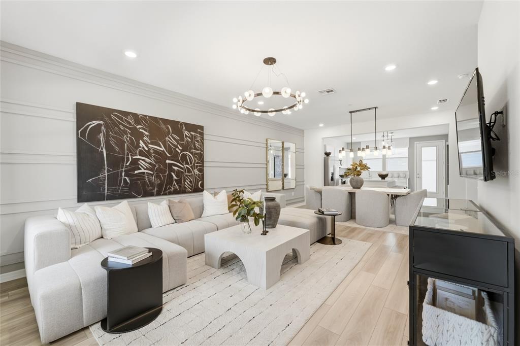 A modern living room features a light gray sectional sofa, a white coffee table, and artwork — 4560 MAPLE WALTZ ALLEY, CLERMONT, FL