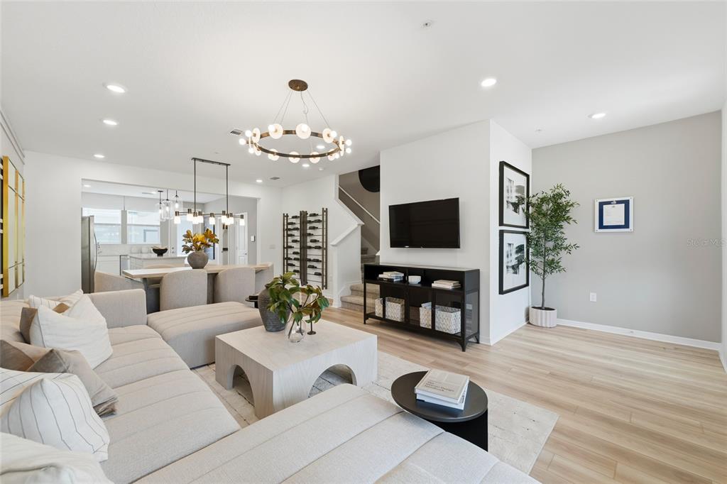 A modern living room with a sectional sofa, coffee table, television, and open dining area — 4560 MAPLE WALTZ ALLEY, CLERMONT, FL