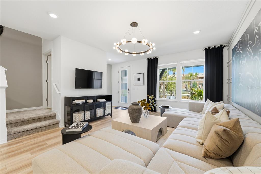 A modern living room features a beige sectional sofa, a coffee table, and a television — 4560 MAPLE WALTZ ALLEY, CLERMONT, FL