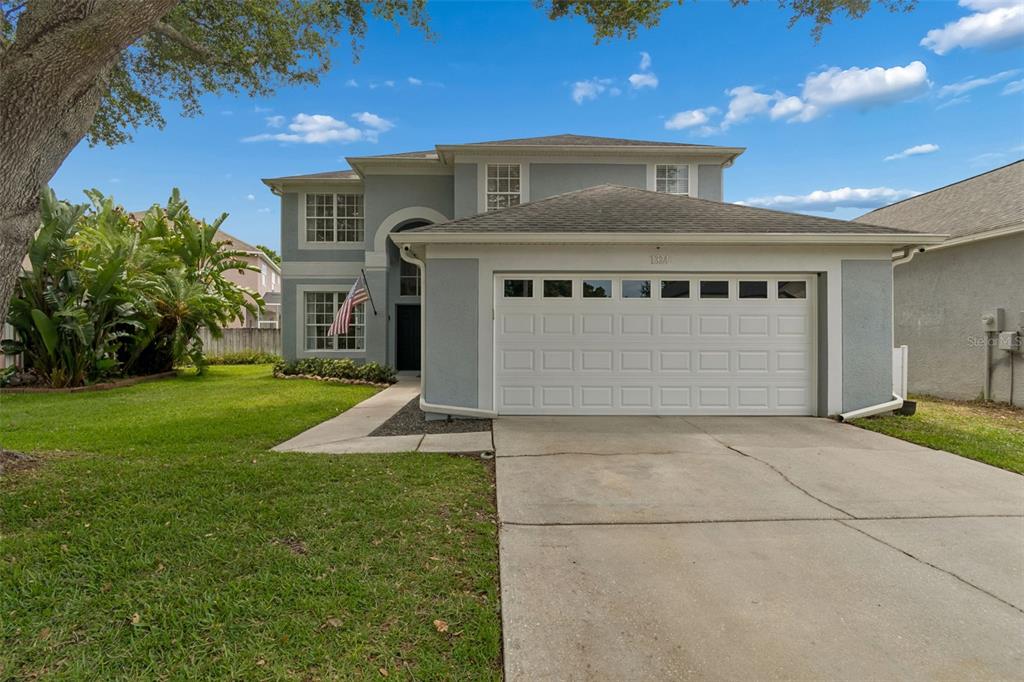 A two-story house with a gray stucco exterior, a two-car garage, and a front lawn — 1324 BROOKE VIEW DRIVE, ODESSA, FL