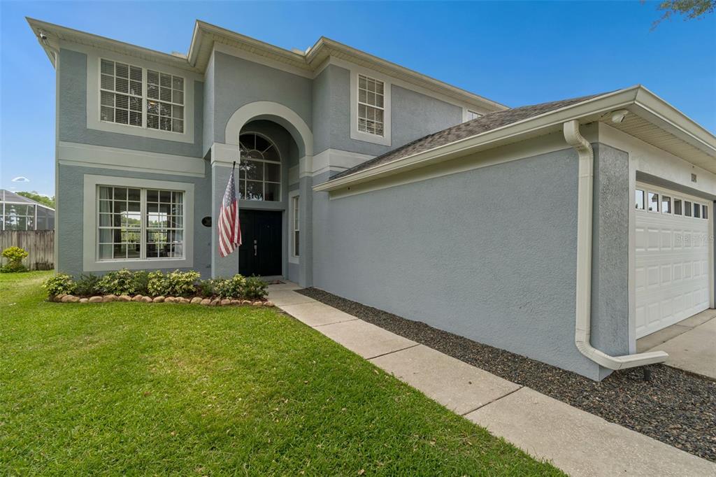 A two-story house with a gray stucco exterior, a front-facing garage, and an arched entryway — 1324 BROOKE VIEW DRIVE, ODESSA, FL