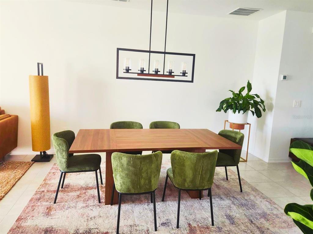 A dining room features a wooden table, green corduroy chairs, and a rectangular pendant light — 4615 WANDSWORTH WAY, DAVENPORT, FL