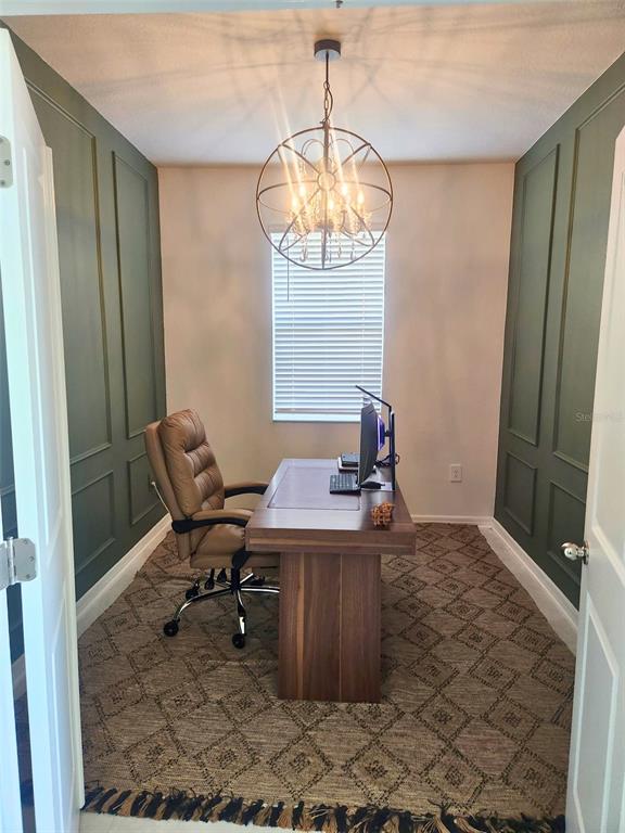 A home office features green paneled walls, a wooden desk, and a spherical chandelier — 4615 WANDSWORTH WAY, DAVENPORT, FL