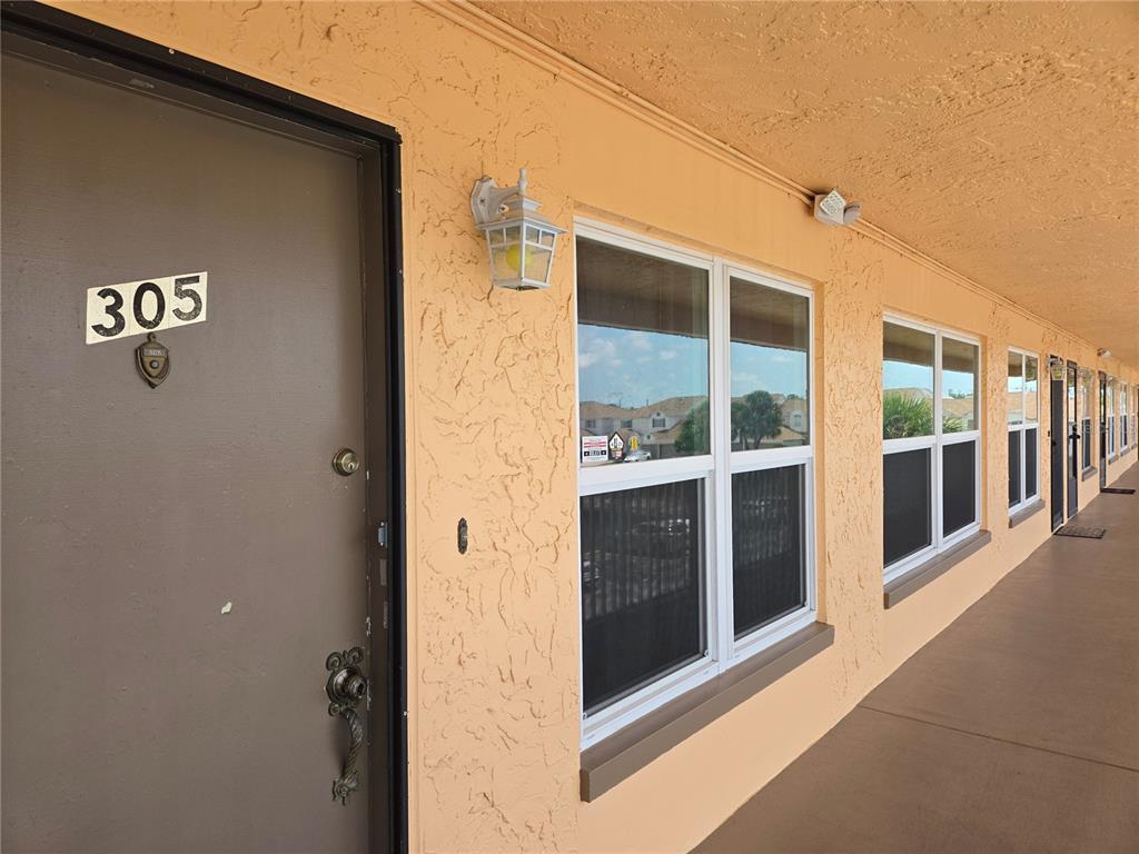 An exterior view of a brown apartment door numbered 305 with adjacent windows — 6400 46TH AVENUE N UNIT 305, KENNETH CITY, FL