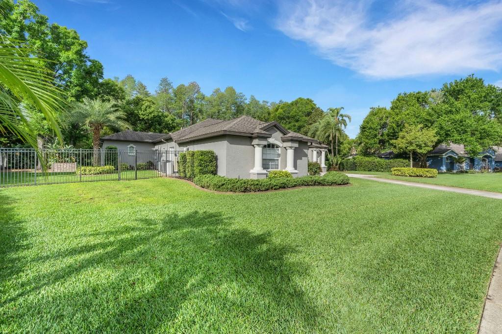 A gray single-story house with a fenced yard and a large green lawn — 18212 KEYSTONE GROVE BOULEVARD, ODESSA, FL