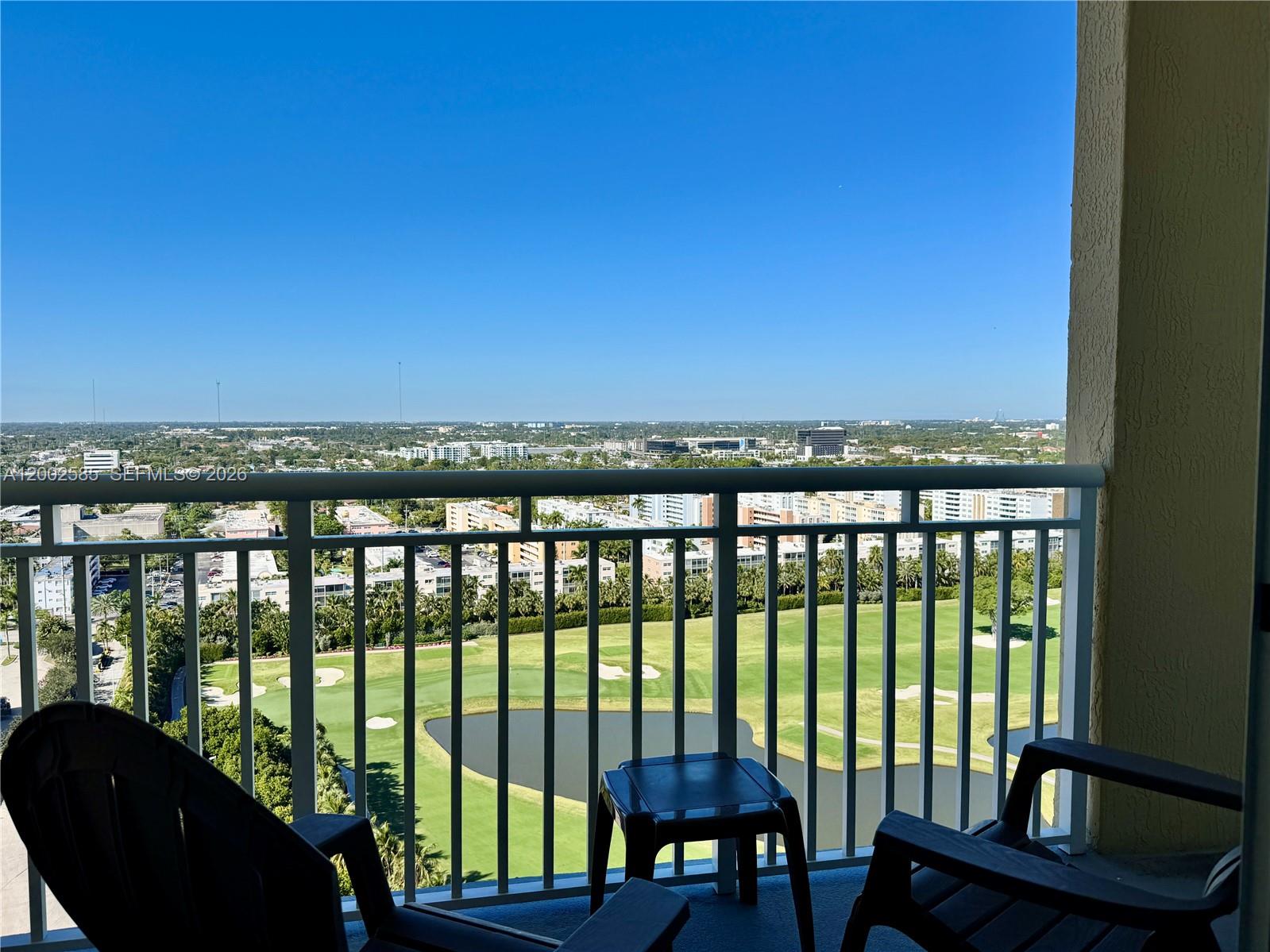 A balcony with two chairs and a small table overlooks a golf course and city — 1745 E Hallandale Beach Blvd # 2001W, Hallandale Beach FL 33009, HALLANDALE BEACH, FL