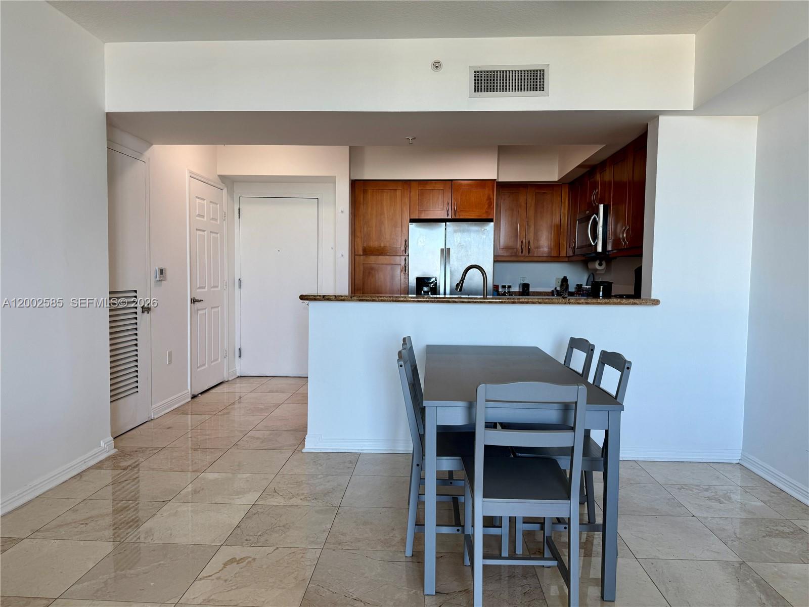 A dining area with a gray table and chairs sits before an open kitchen — 1745 E Hallandale Beach Blvd # 2001W, Hallandale Beach FL 33009, HALLANDALE BEACH, FL