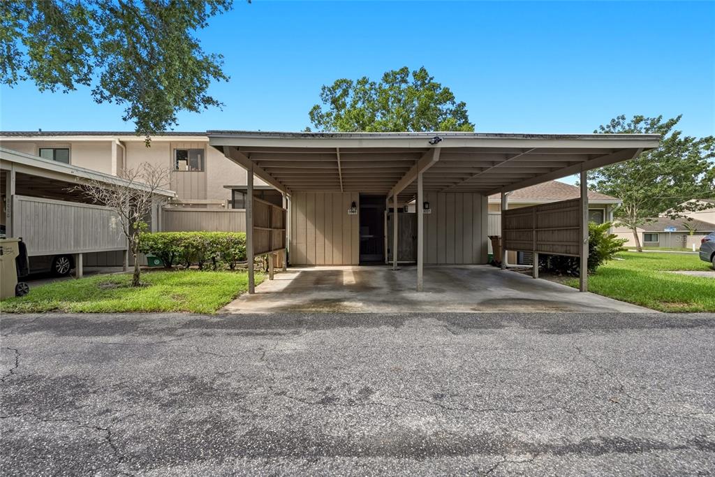 A beige townhouse exterior features a covered carport and a small patch of front lawn — 8003 JASMINE DRIVE UNIT 8003, TAMPA, FL