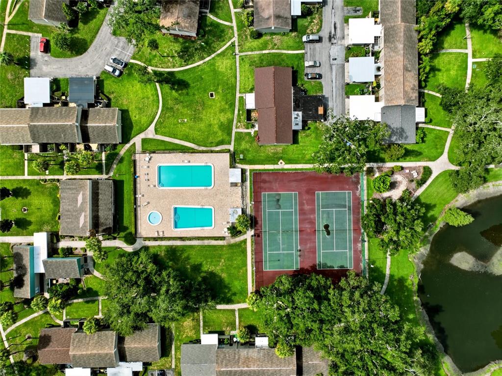 An aerial view shows a residential complex with a swimming pool and two tennis courts — 8003 JASMINE DRIVE UNIT 8003, TAMPA, FL