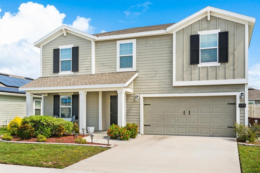 A two-story house with light green siding, a two-car garage, and a front porch — 545 S ANDREA CIRCLE, HAINES CITY, FL
