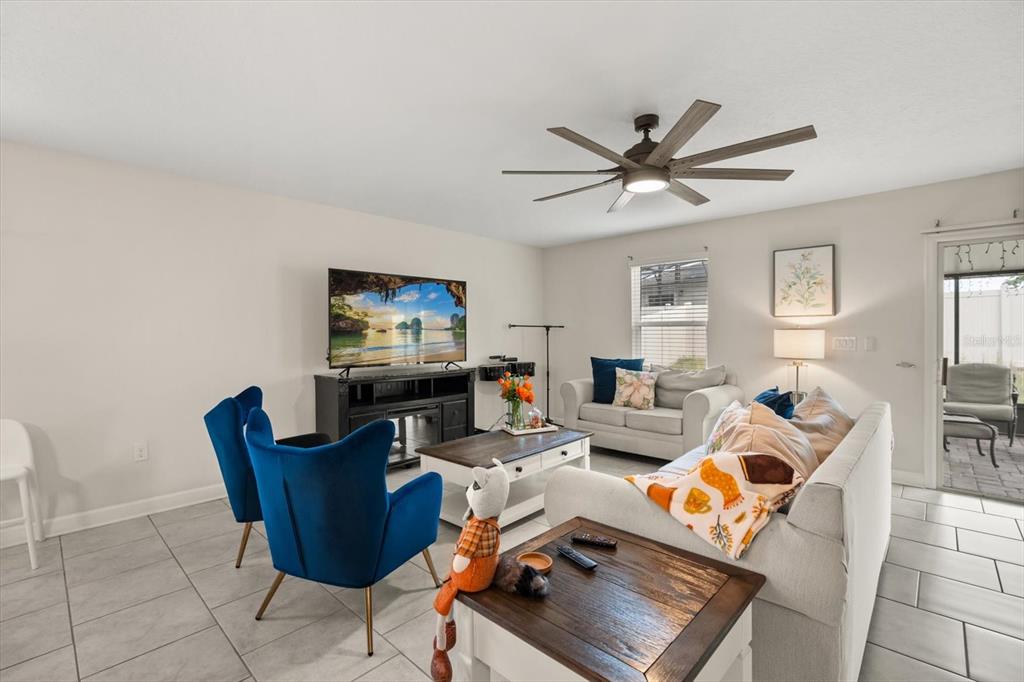 A living room features a television, blue armchairs, a sofa, and a ceiling fan — 545 S ANDREA CIRCLE, HAINES CITY, FL