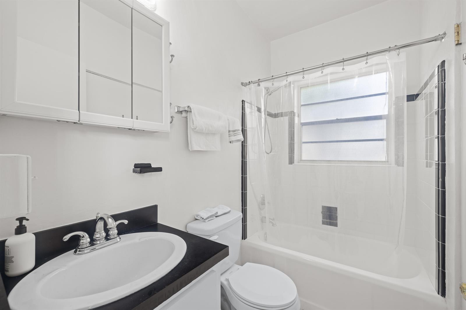 A bathroom features a white vanity with a black countertop, toilet, and a shower-tub combo — 172 N County Road # 5, Palm Beach FL 33480, PALM BEACH, FL