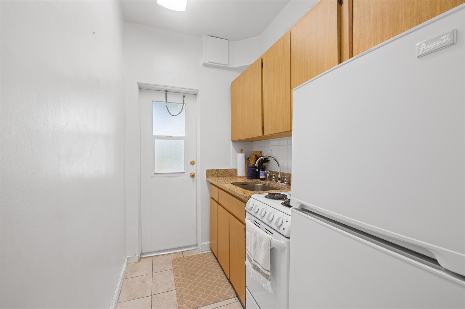 A small galley kitchen features light wood cabinets, granite countertops, and a white refrigerator — 172 N County Road # 5, Palm Beach FL 33480, PALM BEACH, FL