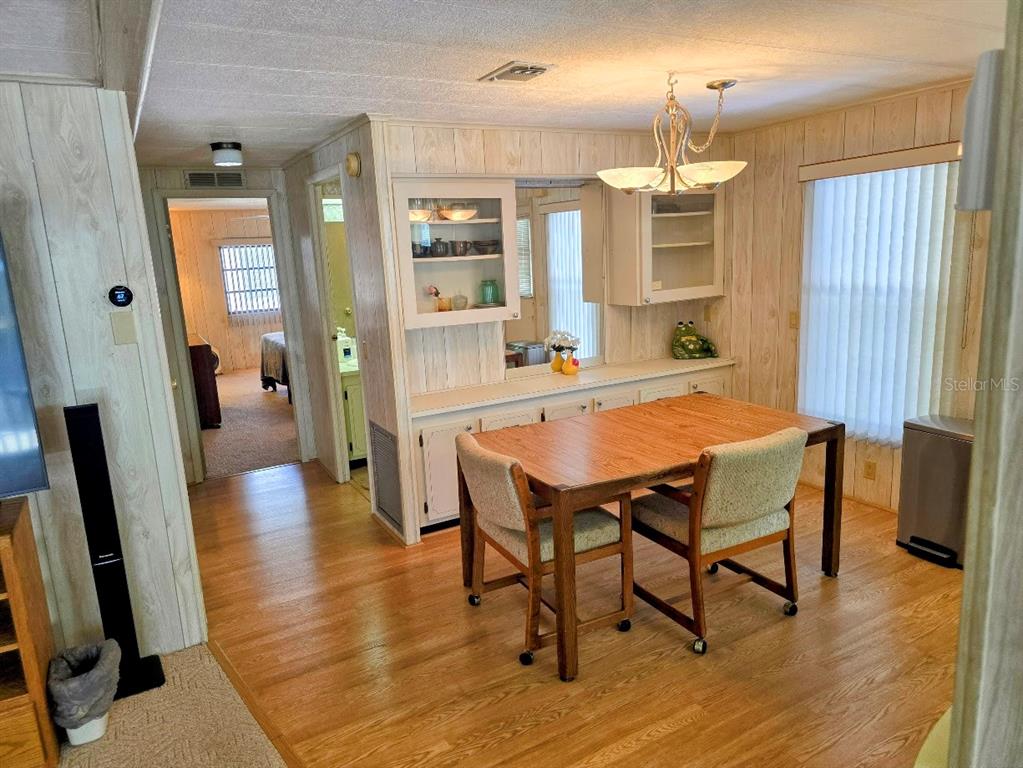 A dining area features wood-paneled walls, a wooden table with two chairs, and built-in cabinetry — 12501 ULMERTON ROAD UNIT 188, LARGO, FL