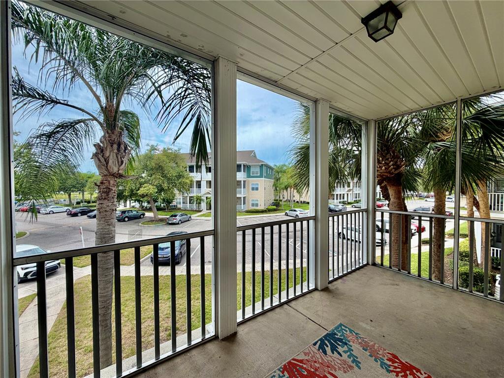 A screened-in balcony overlooks a parking lot and apartment buildings with palm trees — 4802 51ST STREET W UNIT 409, BRADENTON, FL
