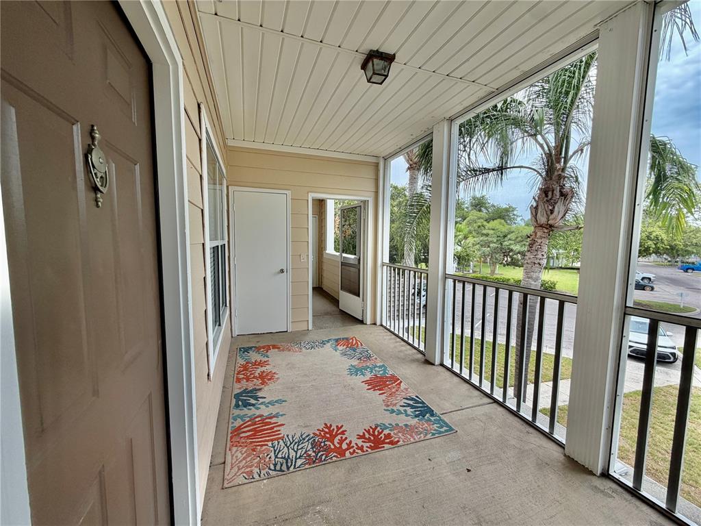 A covered balcony features a concrete floor, a patterned rug, and a screened-in railing — 4802 51ST STREET W UNIT 409, BRADENTON, FL
