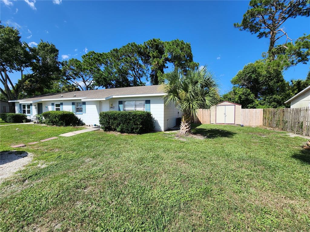 A single-story white house with a front lawn, a palm tree, and a storage shed — 1917 FERN PALM DRIVE, EDGEWATER, FL