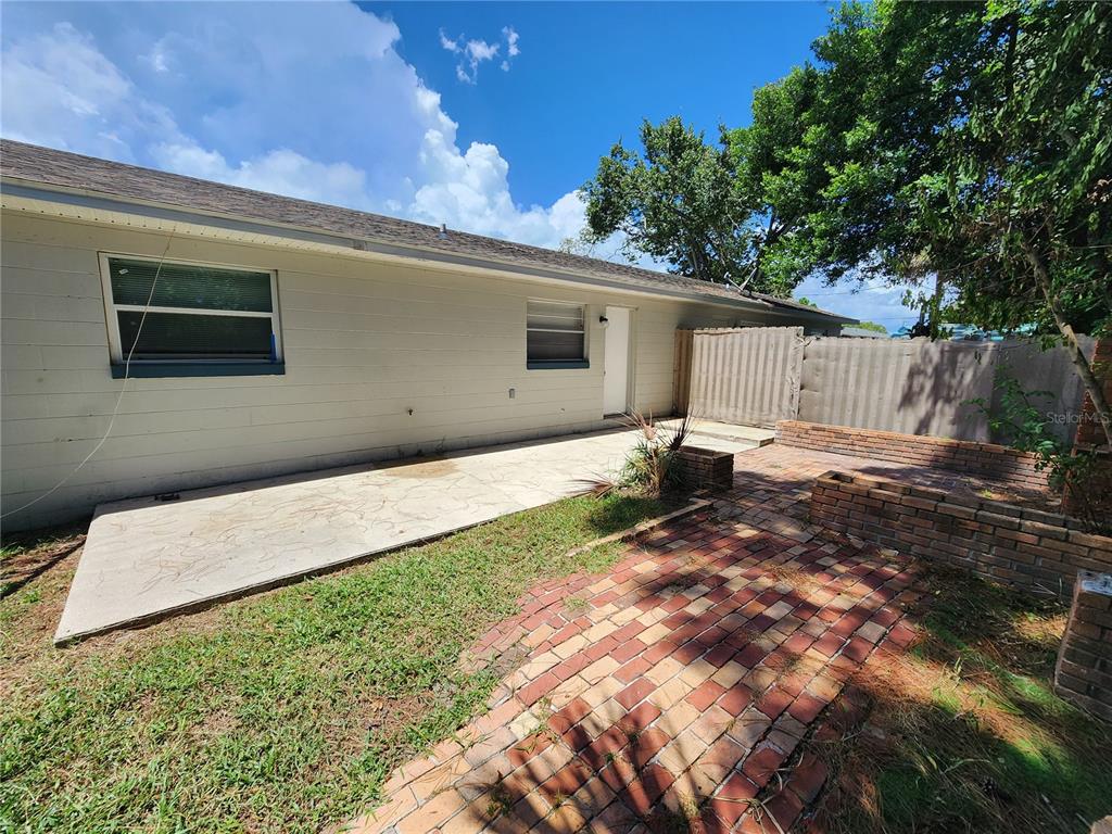 A backyard features a concrete patio, a brick walkway, and a brick planter wall — 1917 FERN PALM DRIVE, EDGEWATER, FL