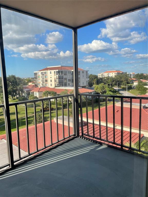 A screened-in balcony overlooks a residential complex with red-tiled roofs and green lawns — 6269 PALMA DEL MAR BOULEVARD S UNIT 501, ST PETERSBURG, FL