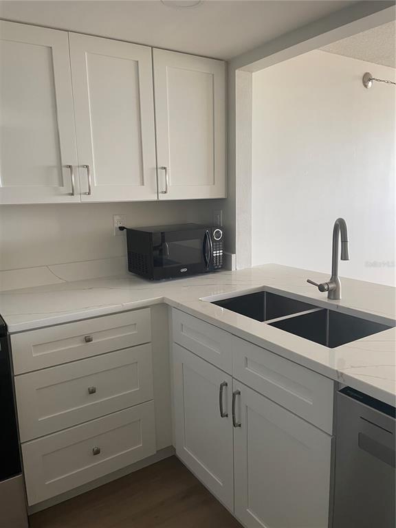 A kitchen with white cabinets, a black microwave, a double sink, and white countertops — 6269 PALMA DEL MAR BOULEVARD S UNIT 501, ST PETERSBURG, FL