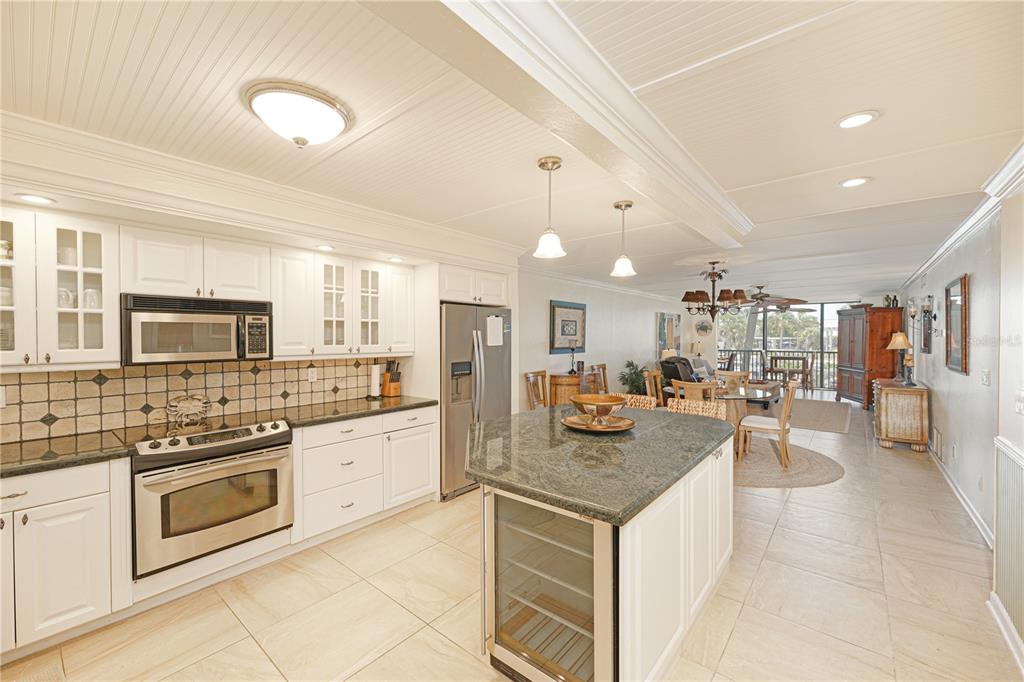 A kitchen with white cabinets, granite countertops, and a central island with a wine cooler — 5600 BEACH WAY DR UNIT 213, SARASOTA, FL