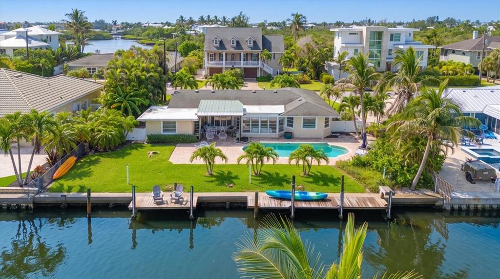 An aerial view of a waterfront house with a swimming pool, lawn, and private dock — 508 83RD STREET, HOLMES BEACH, FL