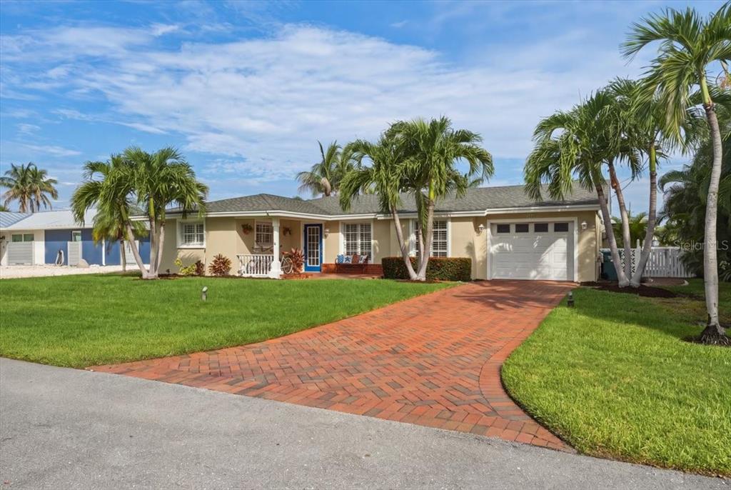 A single-story house with a brick driveway, palm trees, and a blue front door — 508 83RD STREET, HOLMES BEACH, FL