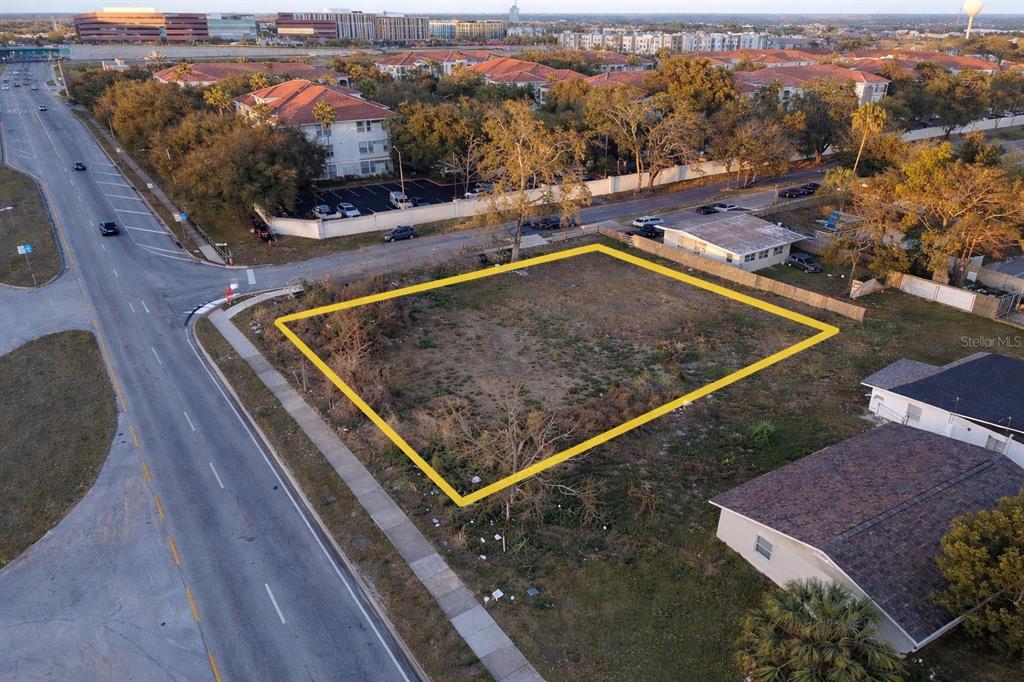 An aerial view shows a vacant, rectangular lot outlined in yellow next to a paved road — 2628 HERBISON DRIVE, ORLANDO, FL