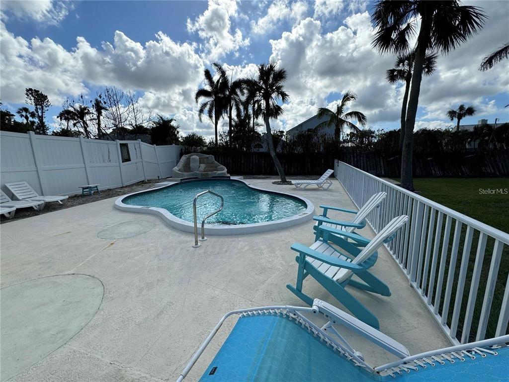 A swimming pool with a rock feature sits on a patio surrounded by lounge chairs — 301 COLONIA LANE W, NOKOMIS, FL