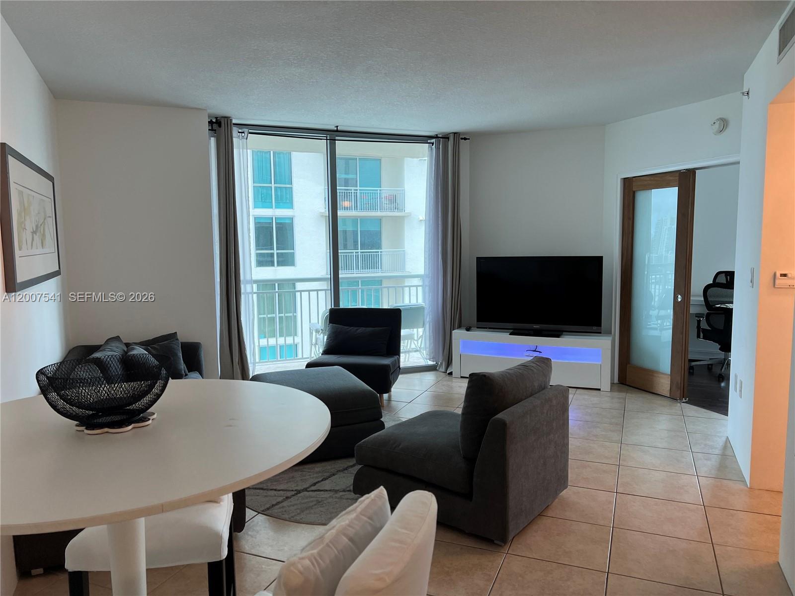 A living room features tile floors, a white dining table, and a balcony view — 9066 SW 73rd Ct # 1703, Miami FL 33156, MIAMI, FL