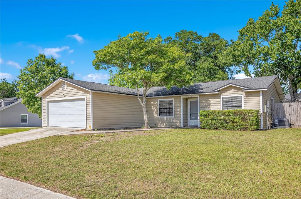 A single-story tan house with a garage, a front lawn, and a large tree — 370 N LAKE AVENUE, APOPKA, FL