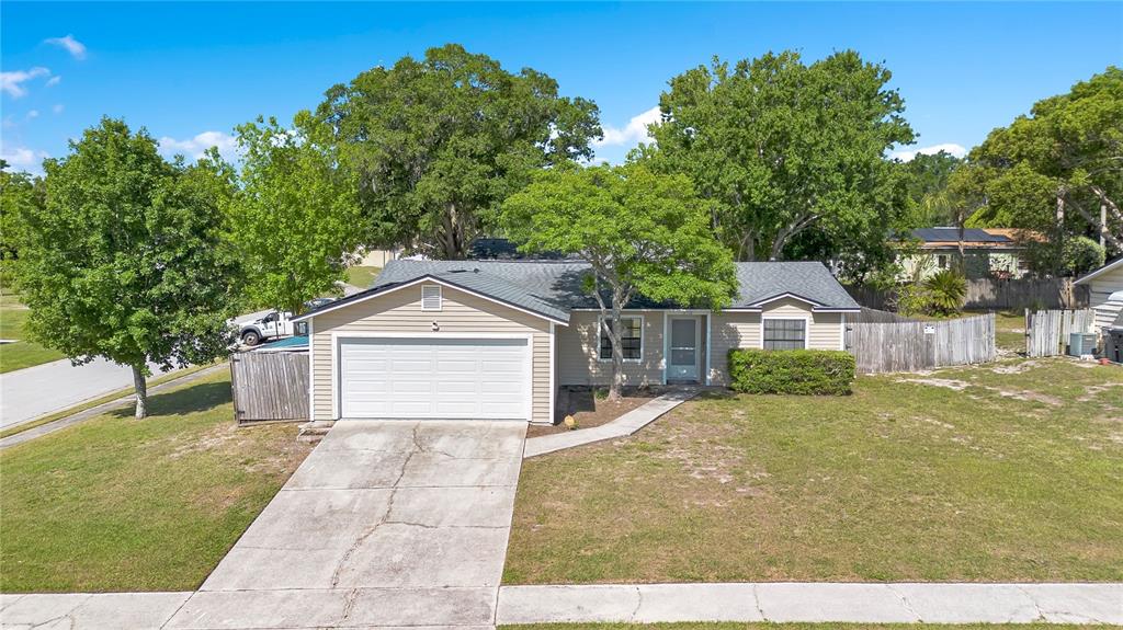 A single-story house with tan siding, a white garage door, and a concrete driveway — 370 N LAKE AVENUE, APOPKA, FL