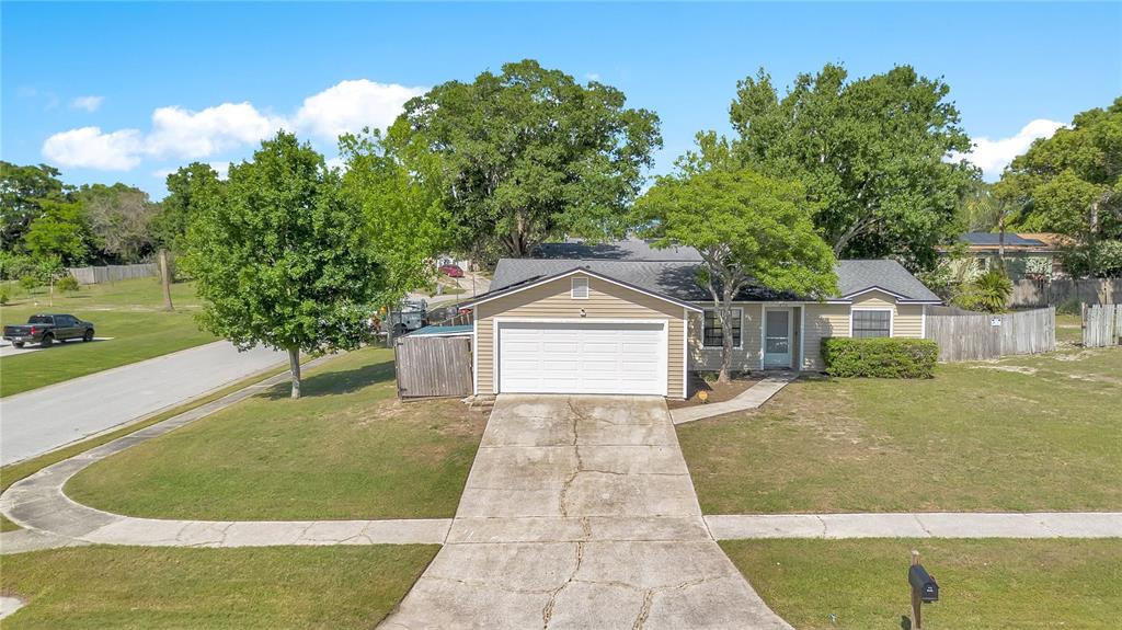 A single-story tan house with a two-car garage and a cracked concrete driveway — 370 N LAKE AVENUE, APOPKA, FL