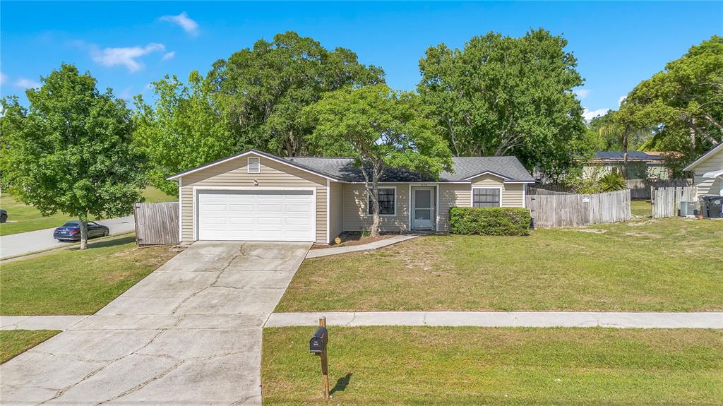 A single-story house with tan siding, a white garage door, and a concrete driveway — 370 N LAKE AVENUE, APOPKA, FL