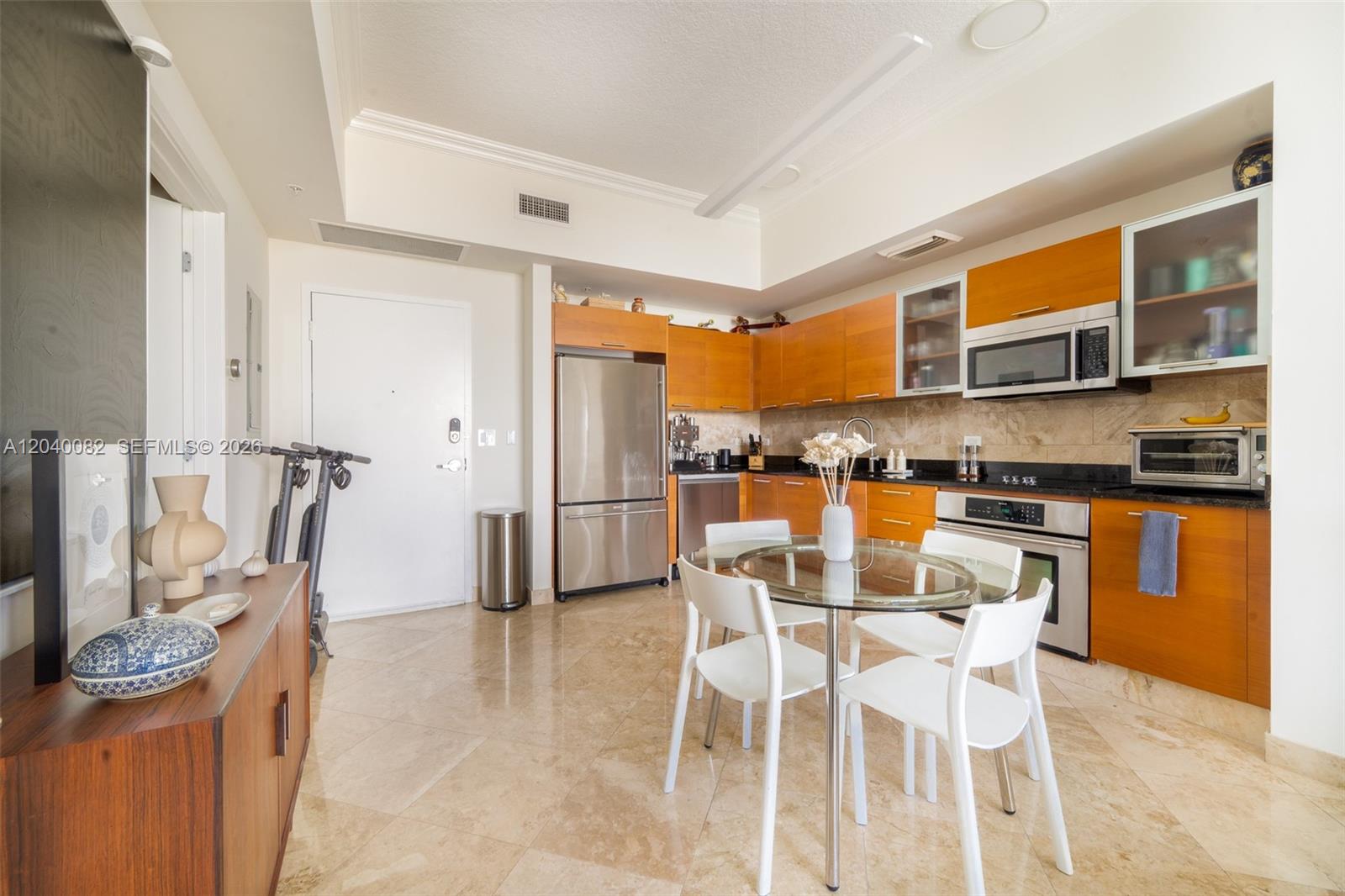 A kitchen features wood cabinets, stainless steel appliances, a glass dining table, and tile floors — 3470 E Coast Ave # H1109, Miami FL 33137, MIAMI, FL