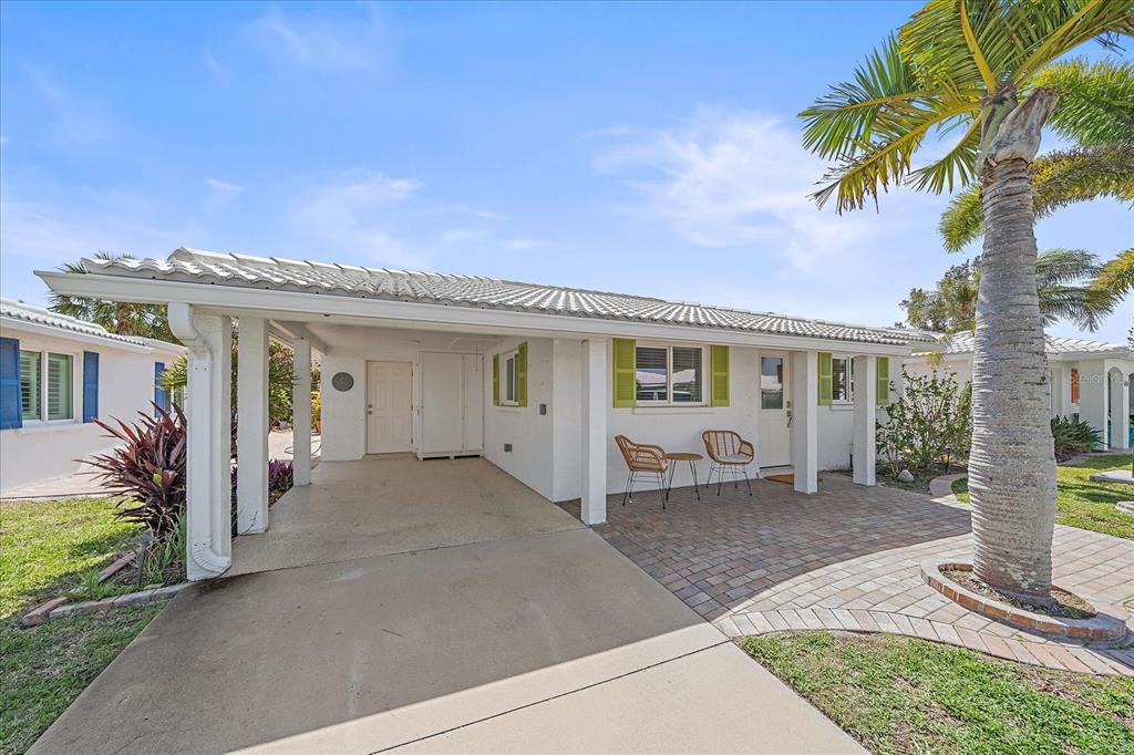 A white house exterior features a carport, a brick patio, and a palm tree — 914 SPANISH DRIVE S UNIT 76, LONGBOAT KEY, FL