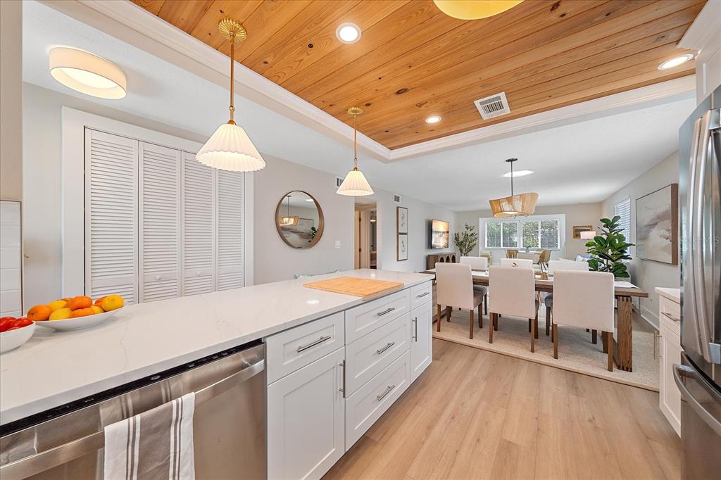 A kitchen island with white cabinets and a quartz countertop overlooks a dining area — 914 SPANISH DRIVE S UNIT 76, LONGBOAT KEY, FL