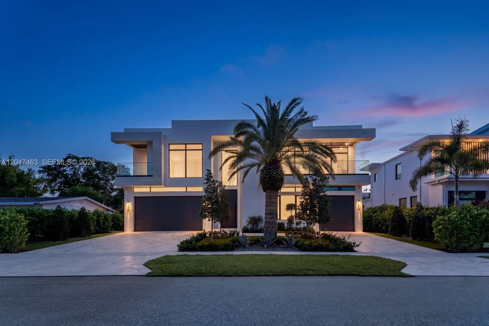 A modern two-story house with a paved driveway, palm tree, and two-car garage at dusk — 1051 NE 2nd Ter, Boca Raton FL 33432, BOCA RATON, FL