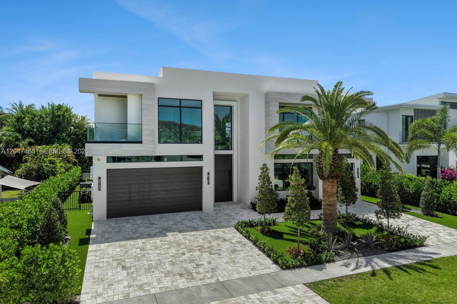 A modern two-story white house features a dark garage door and a prominent palm tree — 1051 NE 2nd Ter, Boca Raton FL 33432, BOCA RATON, FL
