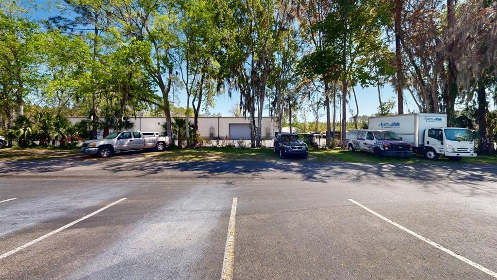 A parking lot sits in front of a commercial building surrounded by tall trees — 605 NW 53RD AVENUE UNIT A-14, GAINESVILLE, FL