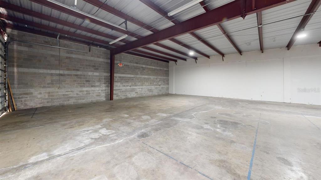 An empty industrial warehouse space features concrete block walls, a concrete floor, and exposed beams — 605 NW 53RD AVENUE UNIT A-14, GAINESVILLE, FL